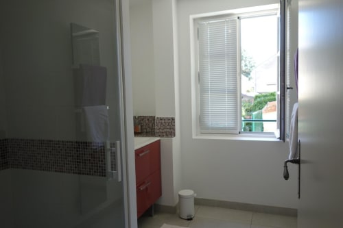 Salle de bain moderne du gîte Le Fassardy à Châteauroux avec douche, vasque rouge et vue sur le jardin