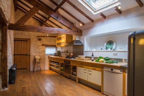Cuisine spacieuse de cottage à Vue Sur Gindou avec poutres apparentes, meubles en bois, électroménagers inox et coin repas