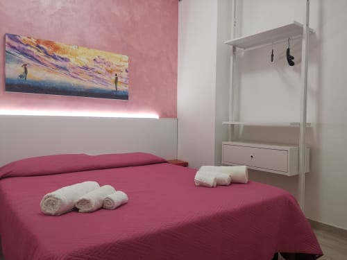 Modern bedroom at Casa Vacanze Del Golfo with pink walls, queen bed, rolled towels, and framed seascape art in Castellammare