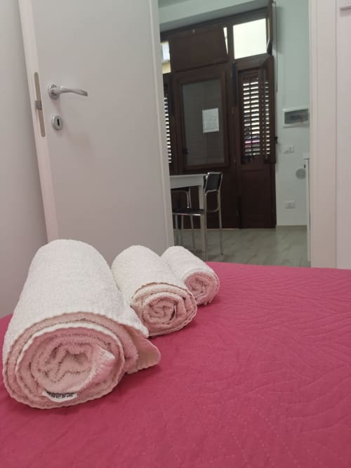 Rolled white and pink towels on pink bedspread in Apartment Rose at Casa Vacanze Del Golfo, Castellammare del Golfo