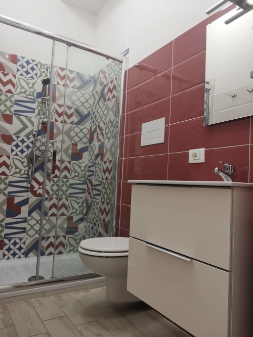 Modern bathroom at Casa Vacanze Del Golfo with red tiles, patterned shower enclosure, and white vanity in Castellammare del