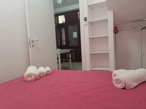 Pink bedroom with rolled towels on bed at Casa Vacanze Del Golfo apartment in Castellammare del Golfo