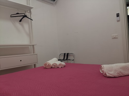 Apartment Rose bedroom with pink bedding, rolled towels, and metal luggage rack at Casa Vacanze Del Golfo in Castellammare