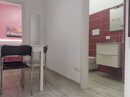 Modern apartment bathroom with red tile walls, white vanity, and mirror at Casa Vacanze Del Golfo, Castellammare del Golfo