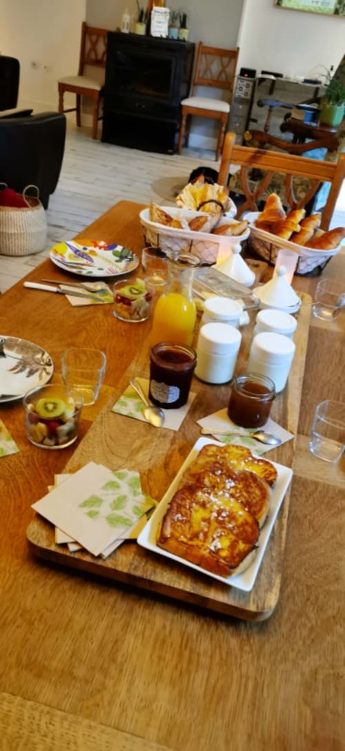 Breakfast spread at Aux Prés Du Berry B&B with pastries, fresh fruit, jams, and juice on wooden table
