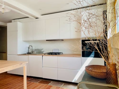 Cuisine blanche moderne avec plan de travail en bois et branches décoratives à la villa Maison Monsieur Léger, Montaut
