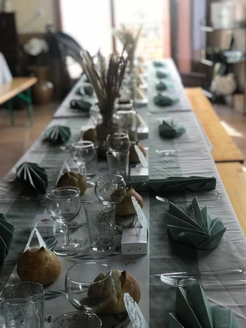 Eleganter Esstisch im BnB La Maison de la Colline mit Gedeck, Wassergläsern und grüner botanischer Dekoration