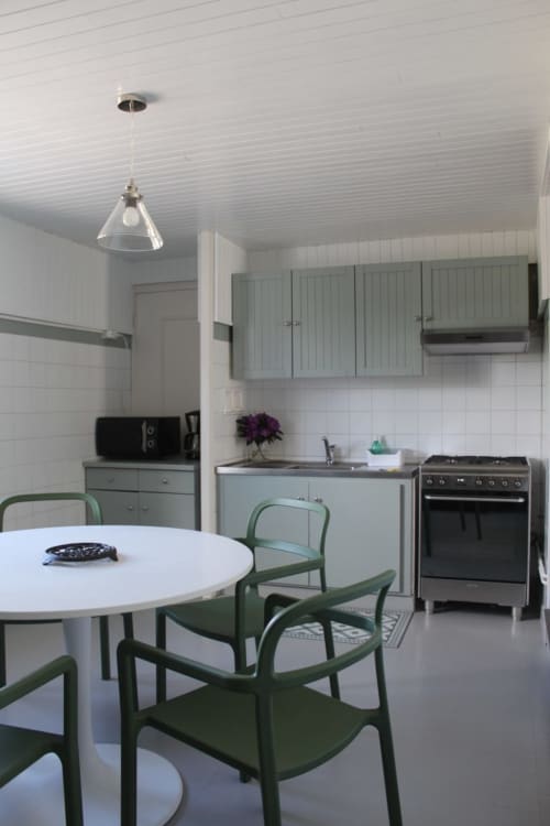 Cuisine et salle à manger modernes des Gîtes De L'odet avec chaises vertes, table blanche et appareils en acier inoxydable