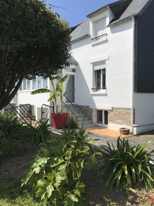 Cottage blanc aux Gîtes De L'odet avec vue jardin, verdure luxuriante et terrasse à Clohars-Fouesnant