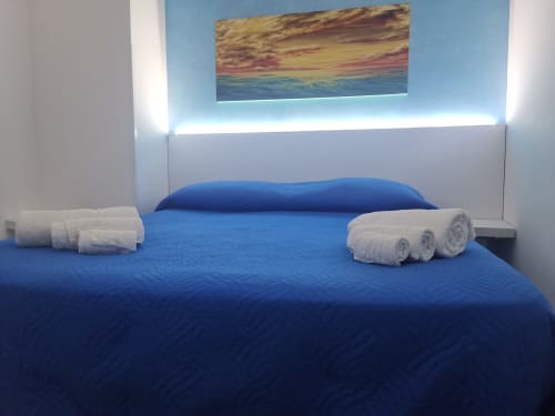 Modern bedroom with blue bedding and white towels at Casa Vacanze Del Golfo apartment in Castellammare del Golfo, with sunset