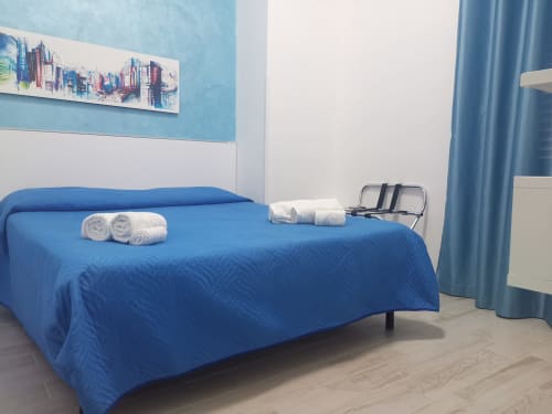 Modern blue bedroom in Casa Vacanze Del Golfo apartment with rolled towels, city skyline art, and mountain views in