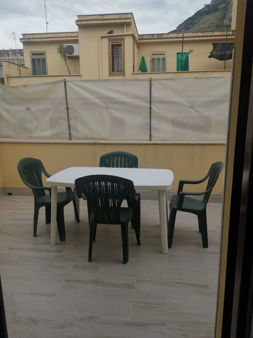 Outdoor terrace with round white table and black chairs at Casa Vacanze Del Golfo, Castellammare del Golfo, with mountain