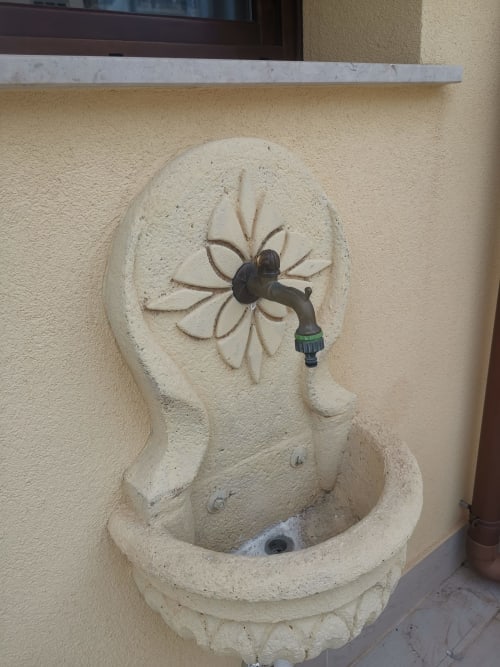 Decorative stone wall fountain with flower design at Casa Vacanze Del Golfo, Castellammare del Golfo