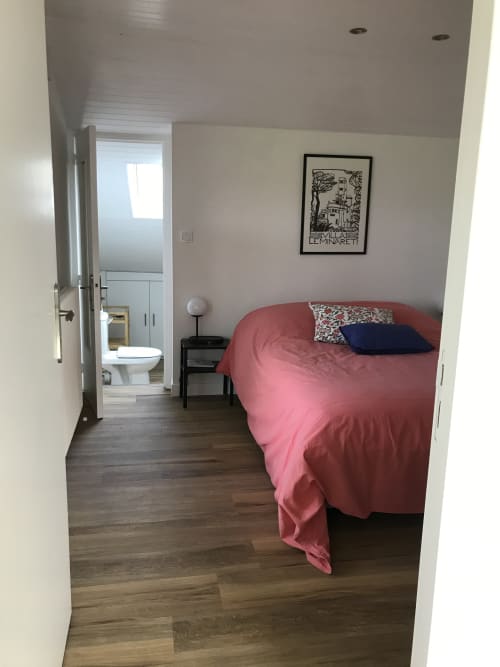 Chambre moderne aux Gîtes De L'odet avec literie corail, salle de bain privée et tableaux encadrés à Clohars-Fouesnant.