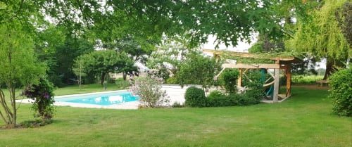 Jardin du Château de Grandmont avec piscine, pelouse soignée, pergola en bois et arbres verdoyants à Blacé, France