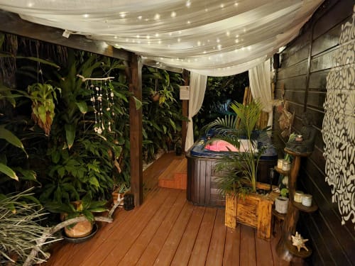 Tropical spa area at Gites Kaladja in Port-Louis with hot tub, lush plants, draped lighting, and wooden deck