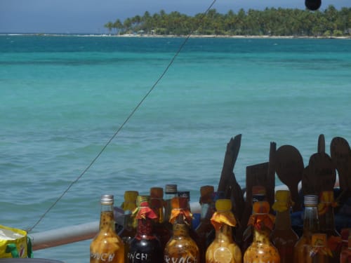 Bouteilles de bière sur le pont d'un bateau avec vue sur les eaux turquoise des Caraïbes et la plage bordée de palmiers à Caribgites, Sainte-Anne