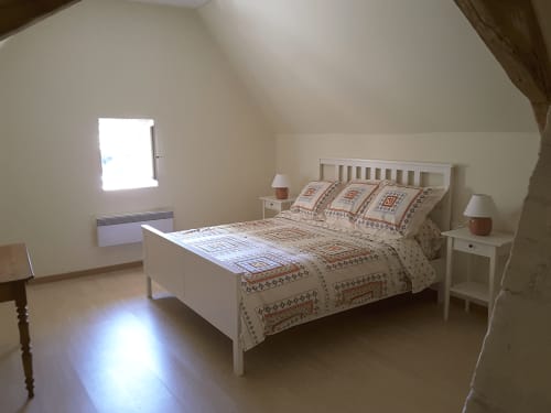 Bright attic bedroom at Château de Ré with white bed, patterned bedding, nightstands, and sloped ceiling in Le Petit