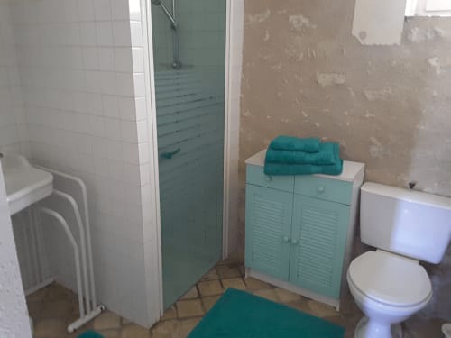 Bathroom at Château de Ré B&B with shower, toilet, turquoise towels and vanity cabinet