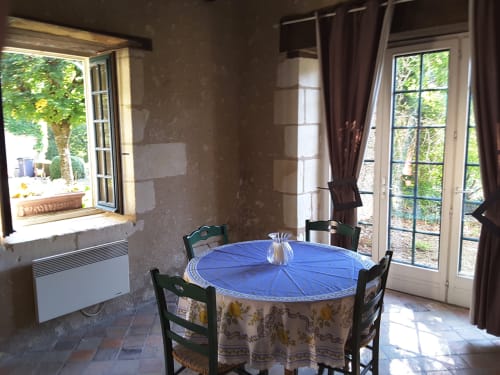 Rustic dining room at Château de Ré in Le Petit Pressigny with round table, green chairs, and garden views through French