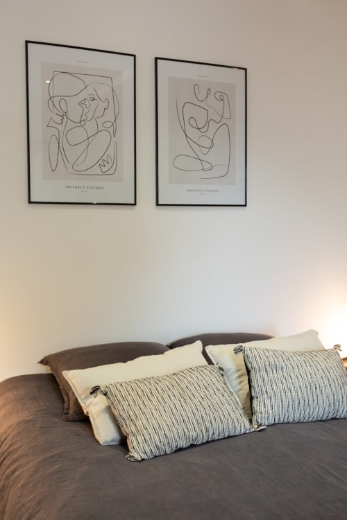 Master bedroom at Manoir de la Nogrie with queen bed, striped pillows, and abstract line art above