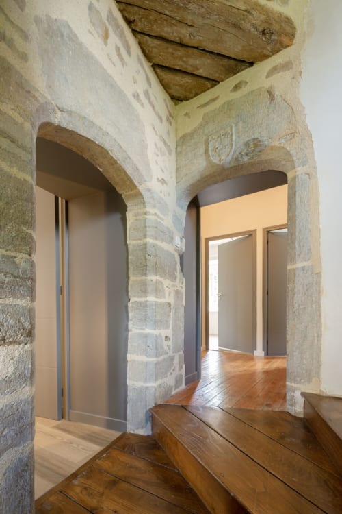 Stone archway entrance to master bedroom at Manoir de la Nogrie with wooden floors and modern amenities