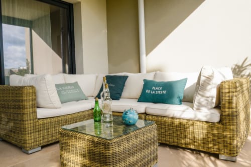 Coin salon en rotin sur la terrasse de My Luxury Home In Provence avec coussins bleu-vert et table en verre