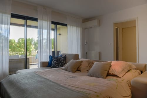 Chambre lumineuse avec lit double, portes-fenêtres, vue sur jardin et équipements modernes dans un appartement provençal