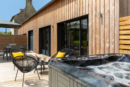 Manoir de la Nogrie outdoor patio with hot tub, modern wooden deck, and lounge chairs