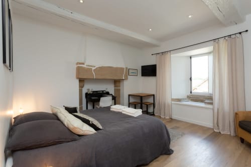 Spacious bedroom at Manoir de la Nogrie with dark bed, fireplace, and modern amenities in Val d'Izé