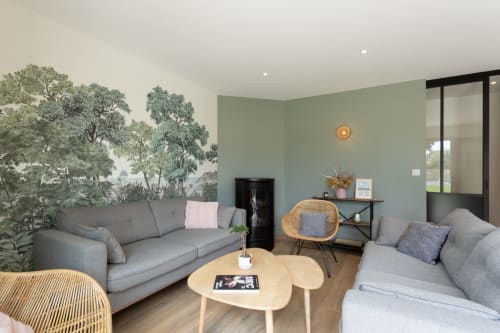 Modern lounge at Manoir de la Nogrie with forest wallpaper, gray sofas, and natural wood accents