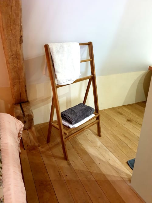 Porte-serviettes en bois avec serviettes blanches et gris foncé dans la chambre chaleureuse du gîte La Dragonne, Bellême