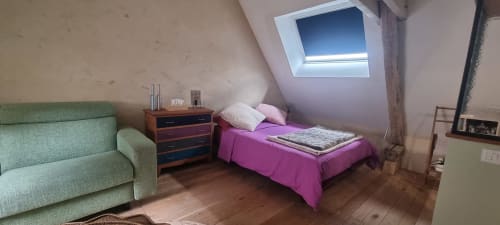 Chambre douillette sous les combles du gîte La Dragonne à Bellême avec lit rose, canapé vert et lucarne