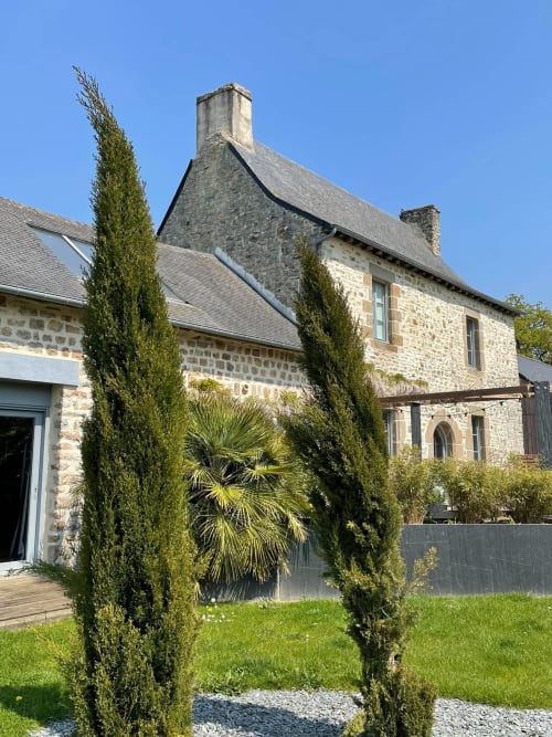 Stone manor house in Val d'Ize with cypress trees and manicured gardens under clear blue sky