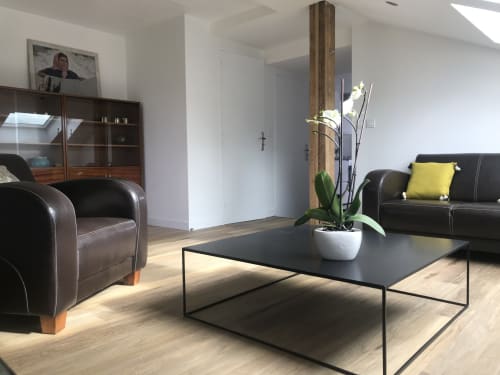 Espace de détente moderne aux Gîtes De L'odet avec sièges en cuir noir, table épurée et orchidée blanche