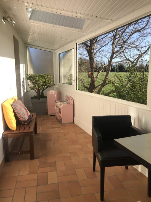 Chambre ensoleillée aux Gîtes De L'odet avec sol en terre cuite, kitchenette vintage rose, coin salon et vue sur
