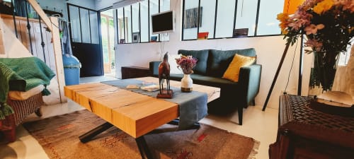 Le salon de La Dragonne BnB à Bellême avec table en bois, canapé bleu canard, fleurs et décoration moderne