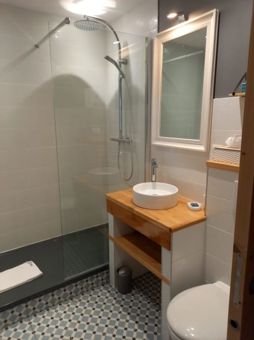 Salle de bain moderne à La Maison De Fleurat avec meuble-lavabo en bois, lavabo rond, douche pluie et carrelage géométrique