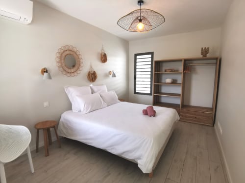 Modern bedroom at Habitation I'SEO in Sainte-Anne with white bedding, wooden furniture, and boho décor