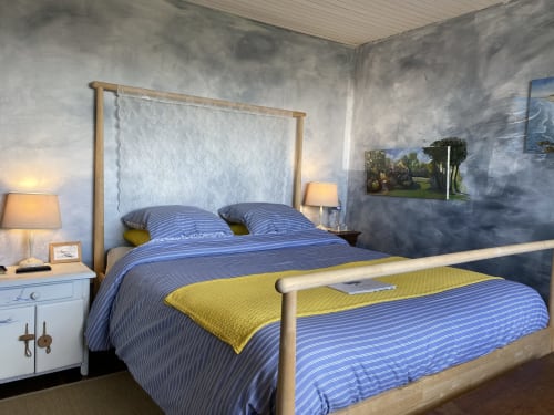 Modern bedroom at L'Ermitage B&B in Saint-Vaast-la-Hougue with blue striped bedding, wooden frame bed, and textured grey