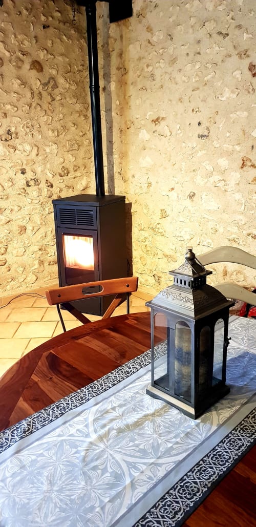 Chambre douillette aux Granges Indigo : poêle à bois, murs en pierre, lanterne décorative et charme rustique français à Fossemagne