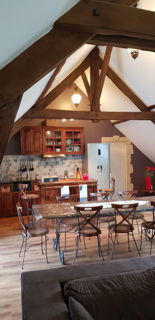 Cuisine ouverte et salle à manger aux Granges Indigo avec poutres apparentes, crédence en pierre et mobilier contemporain.