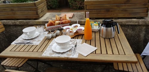 Table de petit-déjeuner en plein air à Les Granges Indigo B&B à Fossemagne, France avec viennoiseries, café et jus d'orange