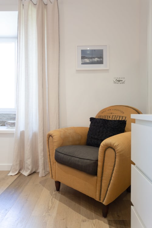 Elegant reading nook in master bedroom at Manoir de la Nogrie with mustard leather armchair, black cushion, and garden views