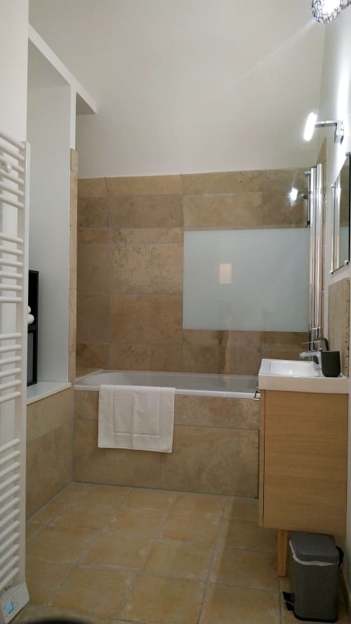 Modern bathroom with travertine tile, soaking tub, sink, and glass shower enclosure at Locacharme cottage in Blois
