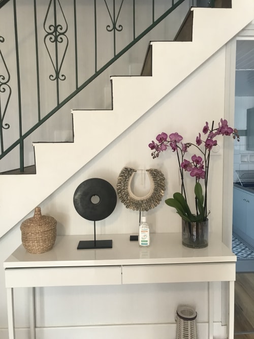 Élégante entrée sous l'escalier du gîte Les Gîtes De L'odet avec console blanche, orchidées pourpres et décoration