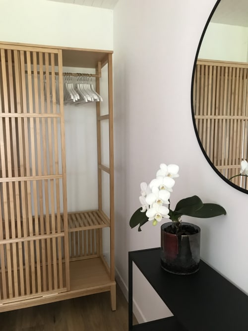 Chambre moderne aux Gîtes De L'odet avec armoire en bois, orchidée blanche, miroir rond et décoration minimaliste