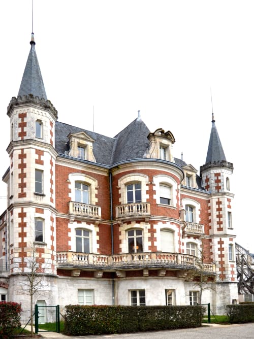Victorian brick castle-style building in Blois, France with red and white stone details and conical towers, home to
