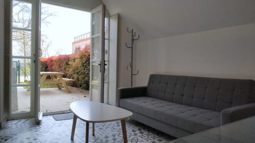 Modern cottage living room at Locacharme Blois with gray sofa, white table, and garden view through glass doors