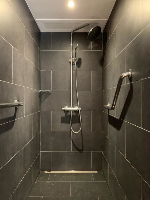 Douche à l'italienne moderne avec carrelage foncé, pommeau de douche cascade et barre de maintien au gîte Vue Sur Gindou à Gindou, France